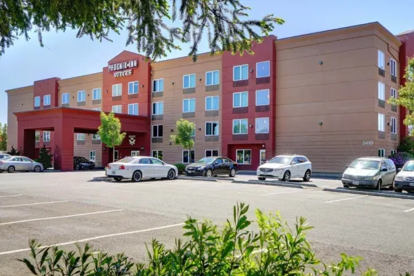 A large hotel with cars parked in front of it.