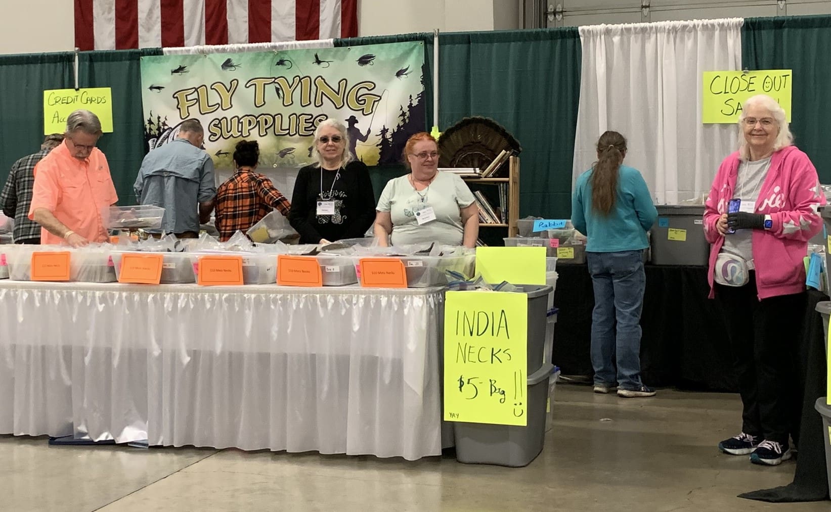 A table with people standing around it at an event.