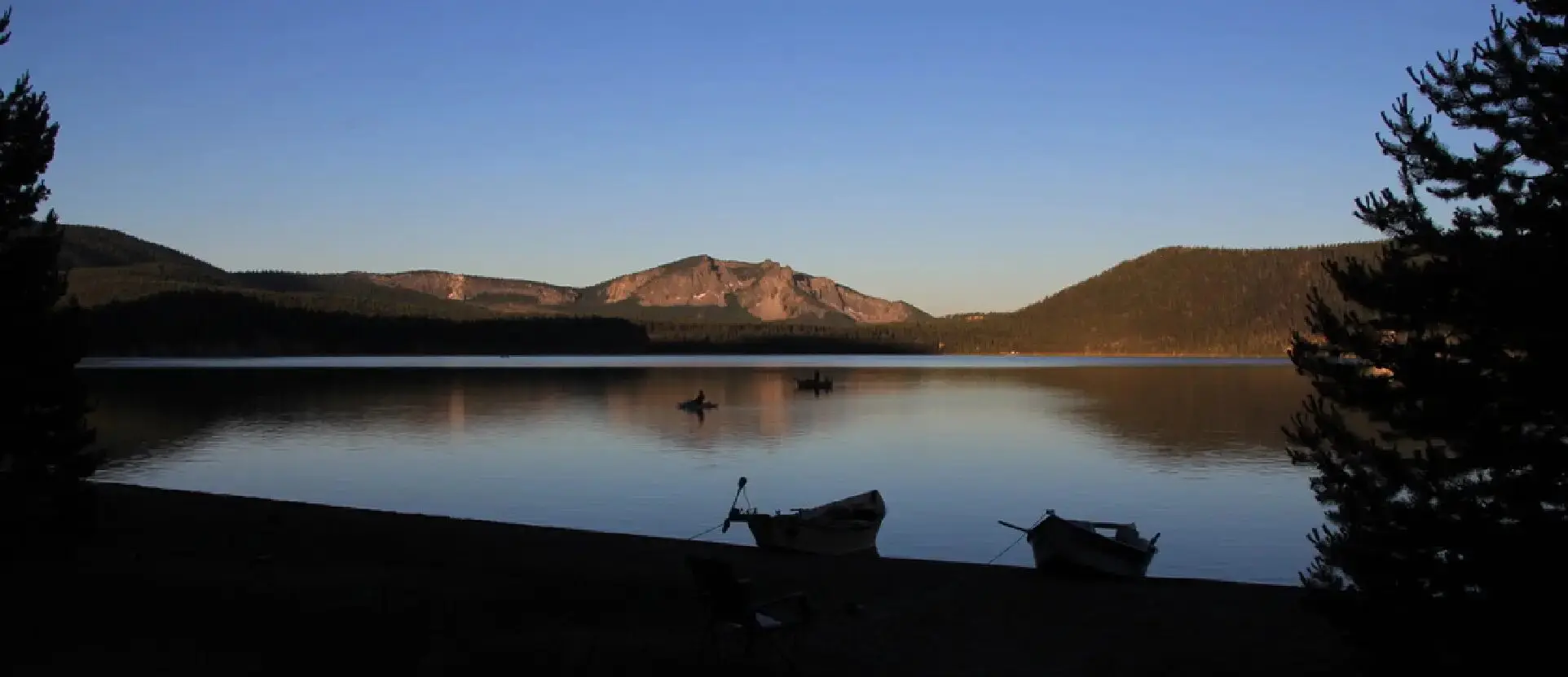 A lake with boats on it and mountains in the background.