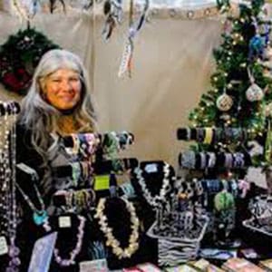 A woman standing in front of a table with jewelry.