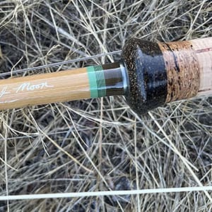 A baseball bat with a wooden handle in the grass.